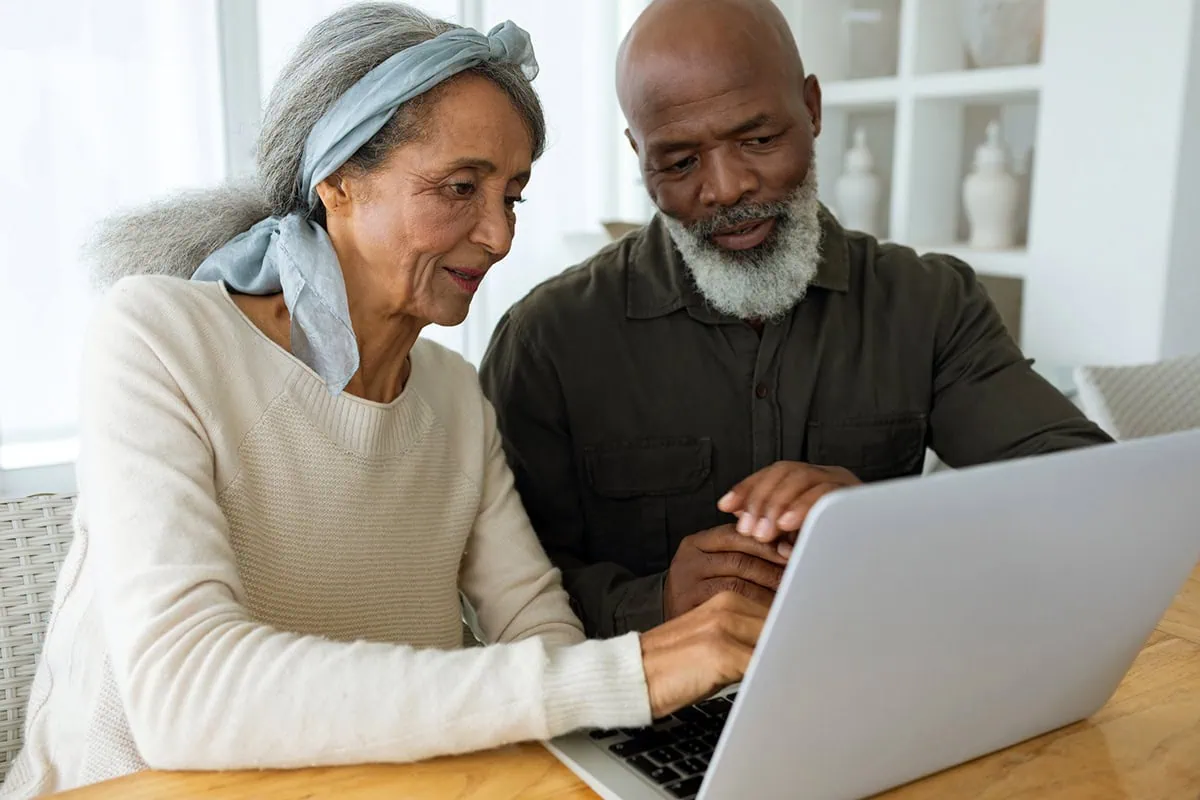 The Medicare Drain: 11 Ways to Stop Your Health Care Costs from Erasing Your Wealth 5 a senior couple look at their laptop.
