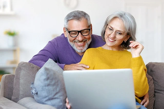 The Opportunity Cost: What You Give Up When You Choose Growth, Value, or Income 2 a senior couple smiles while they look at a laptop.