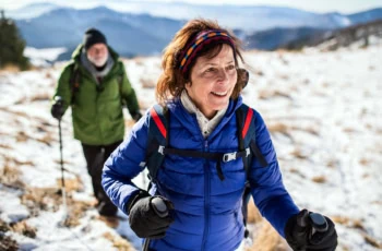 Senior couple with nordic walking poles hiking in snow.
