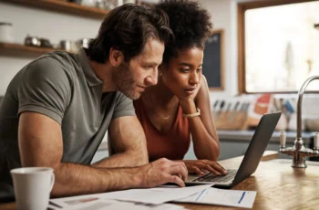 a couple using their laptop while they look at investments.