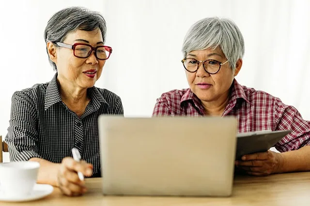 two women smiling while looking at a computer.