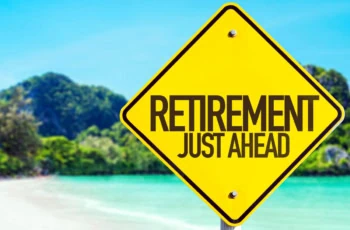 a yellow sign saying retirement just ahead stands in front of a beach.