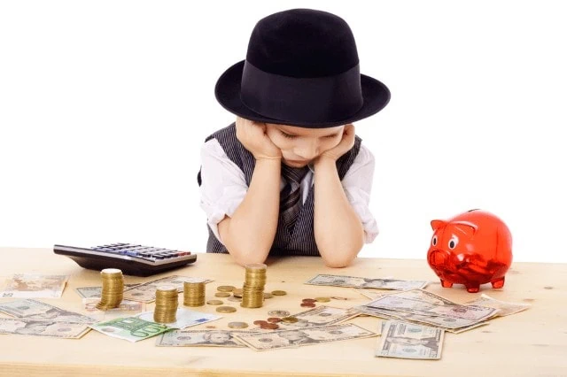 sad child at table with money