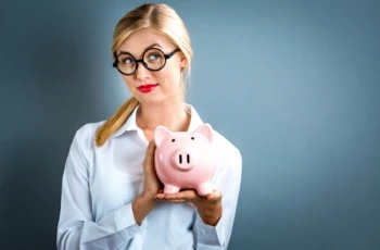 woman with glasses holding piggy bank