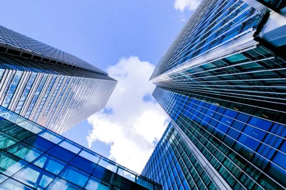 a vertical view of buildings from ground level against a blue sky.