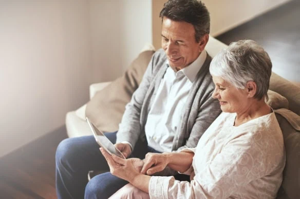 senior couple happily looking at tablet together