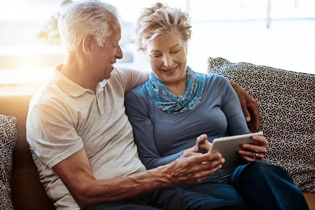 senior couple looking at tablet together on the couch happy