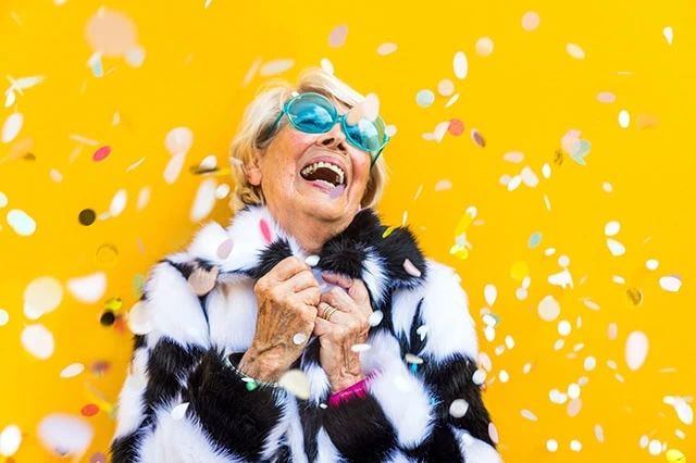a happy senior celebrates while confetti falls around her.