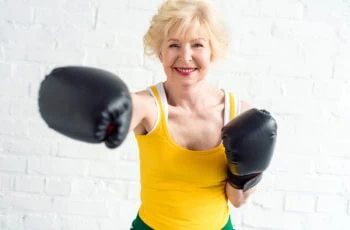 an elderly woman wearing boxing gloves works out.