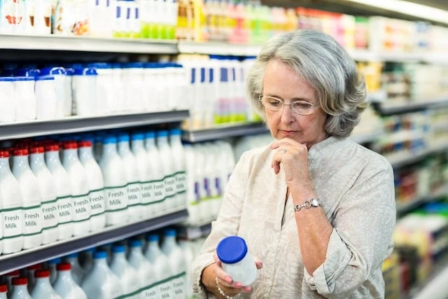 Senior woman buying milk at the supermarket