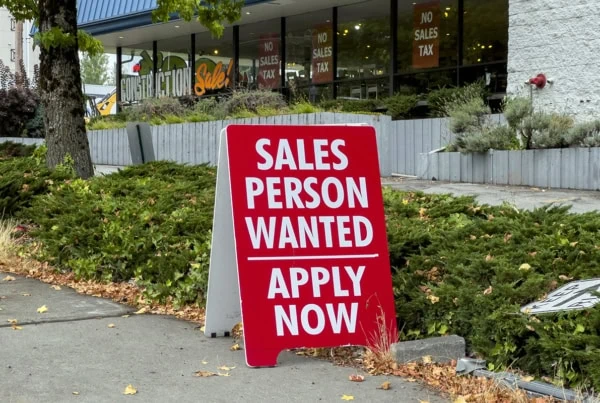 a help wanted sign sits outside of a store.