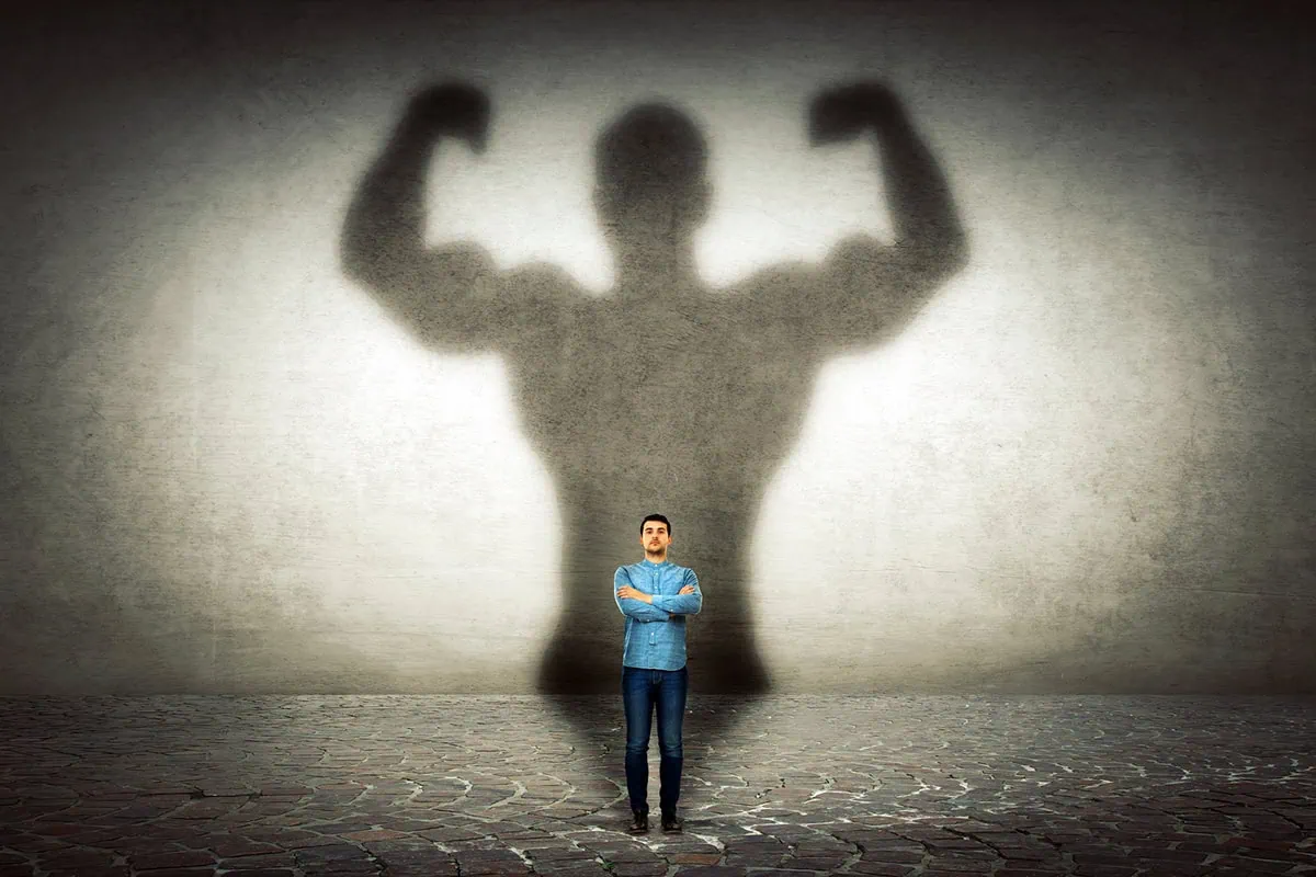 a small person with a very large, muscle-flexing shadow.