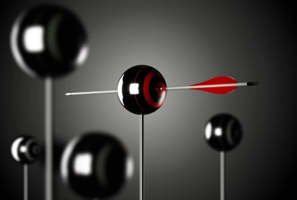 an arrow pierces the eye of a black orb that is held up by a stick and has a red target on its side.