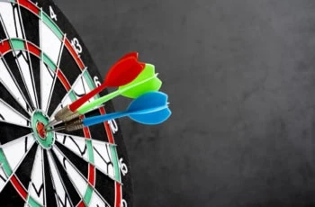 three arrows with red, green, and blue wings hit the bullseye of a dartboard.