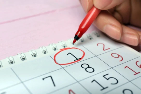 a person circles the first of the month on a calendar.