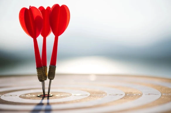 three arrows have hit the bullseye on a target resting on the ground.