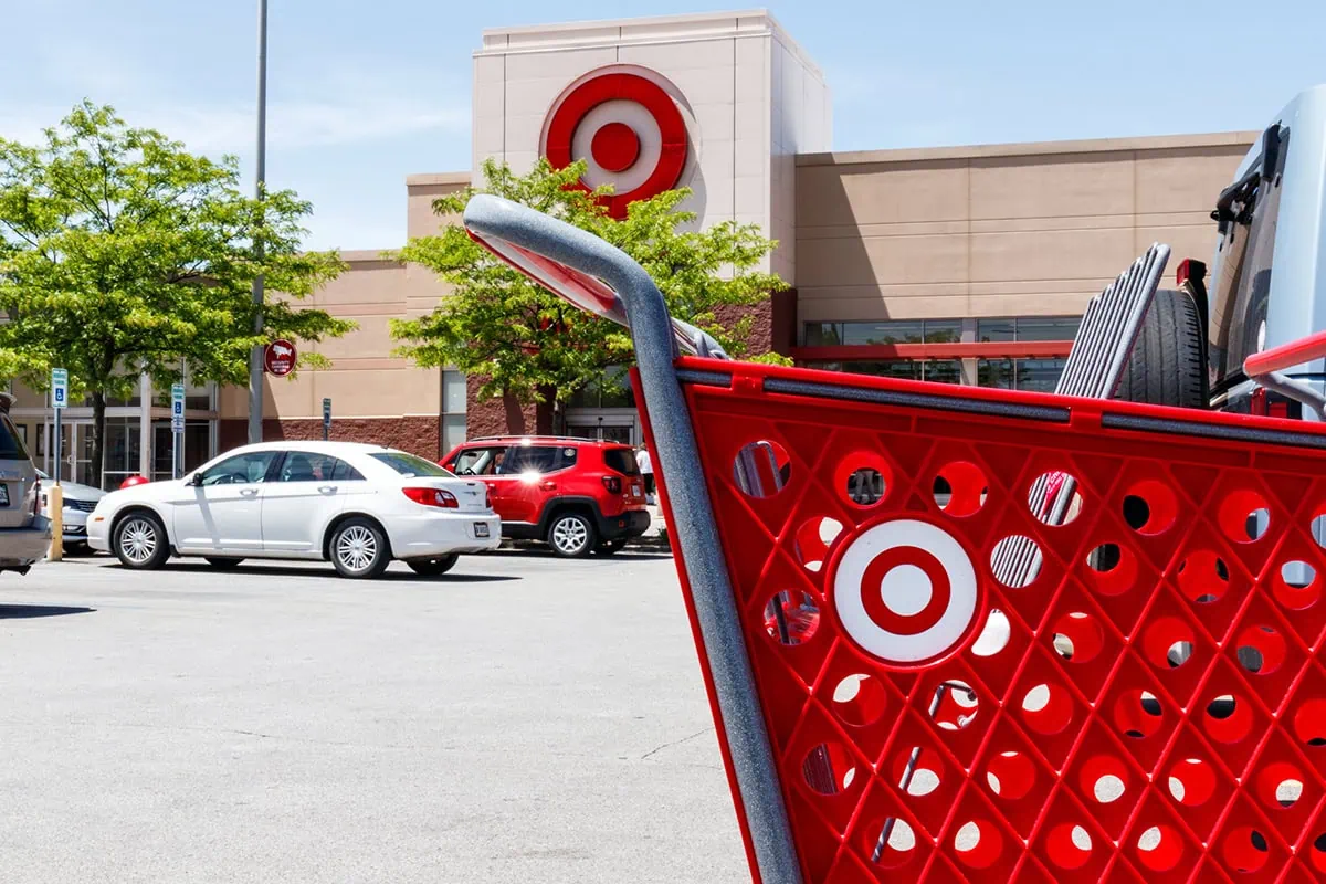 a red target shopping cart in the foreground with a target store in the background.