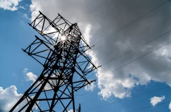 an electric utility tower and lines against a partly cloudy sky.