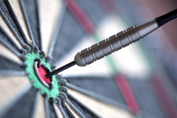 a camera focuses on a dart hitting a bullseye.
