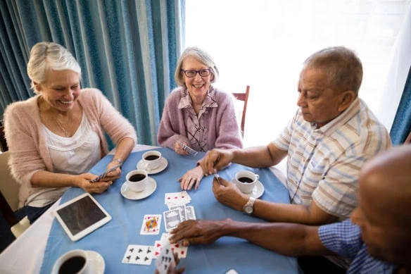 seniors play cards in a senior housing facility.