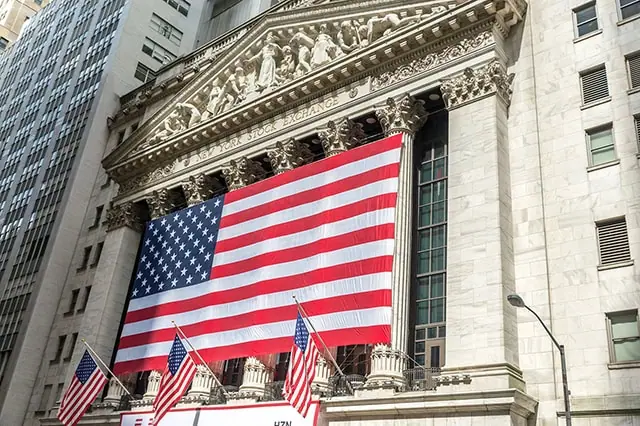 a giant american flag is draped across the new york stock exchange on wall street.