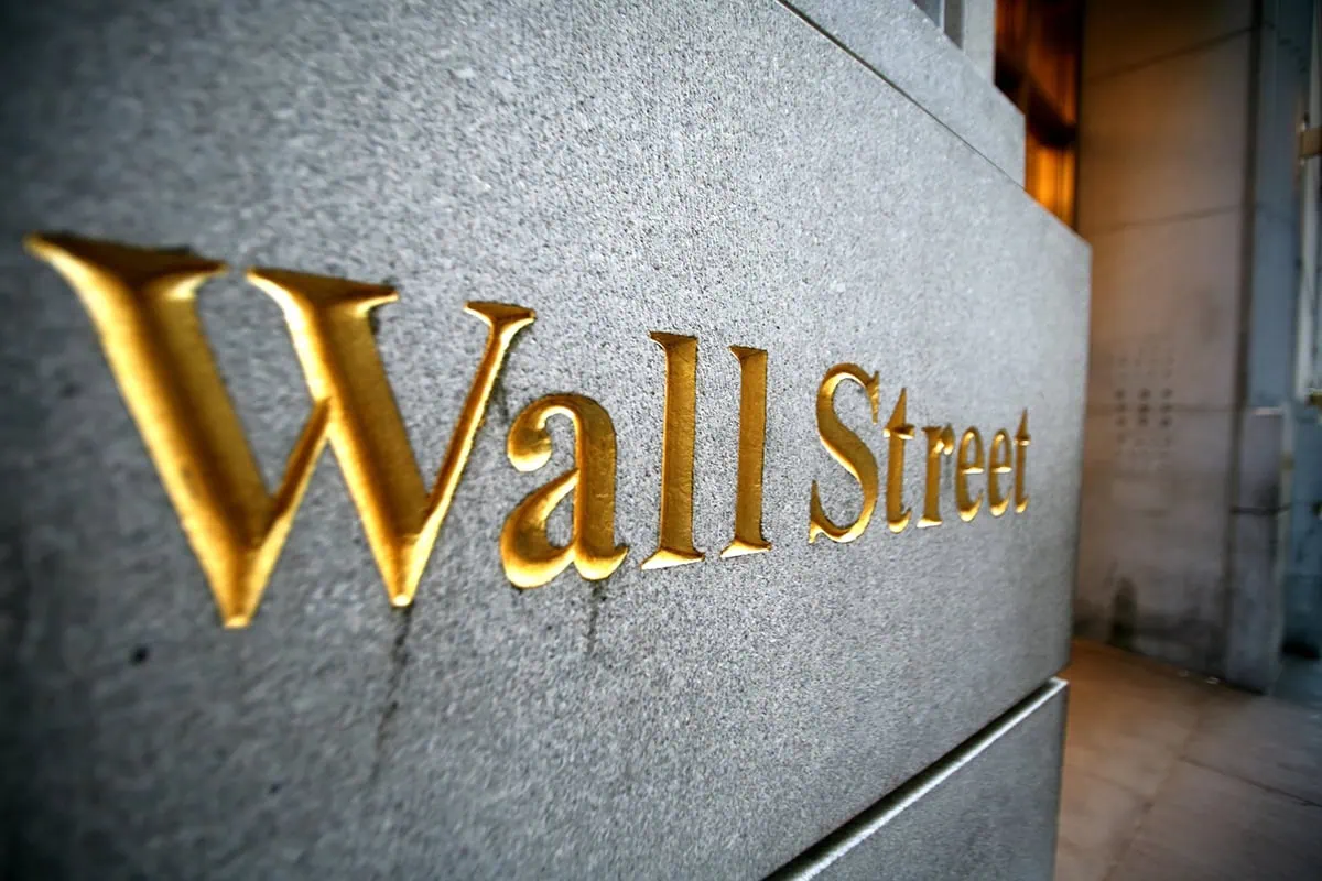 the words wall street are etched in gold into the side of a building on Wall Street in new york city.