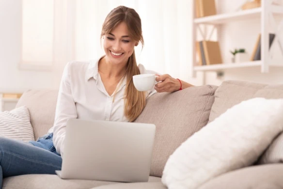 woman working on laptop smiling with coffee