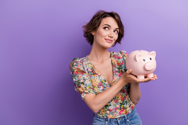 woman looking upward while holding a piggy bank