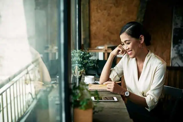 woman-smiling-with-notebook-and-smartphone