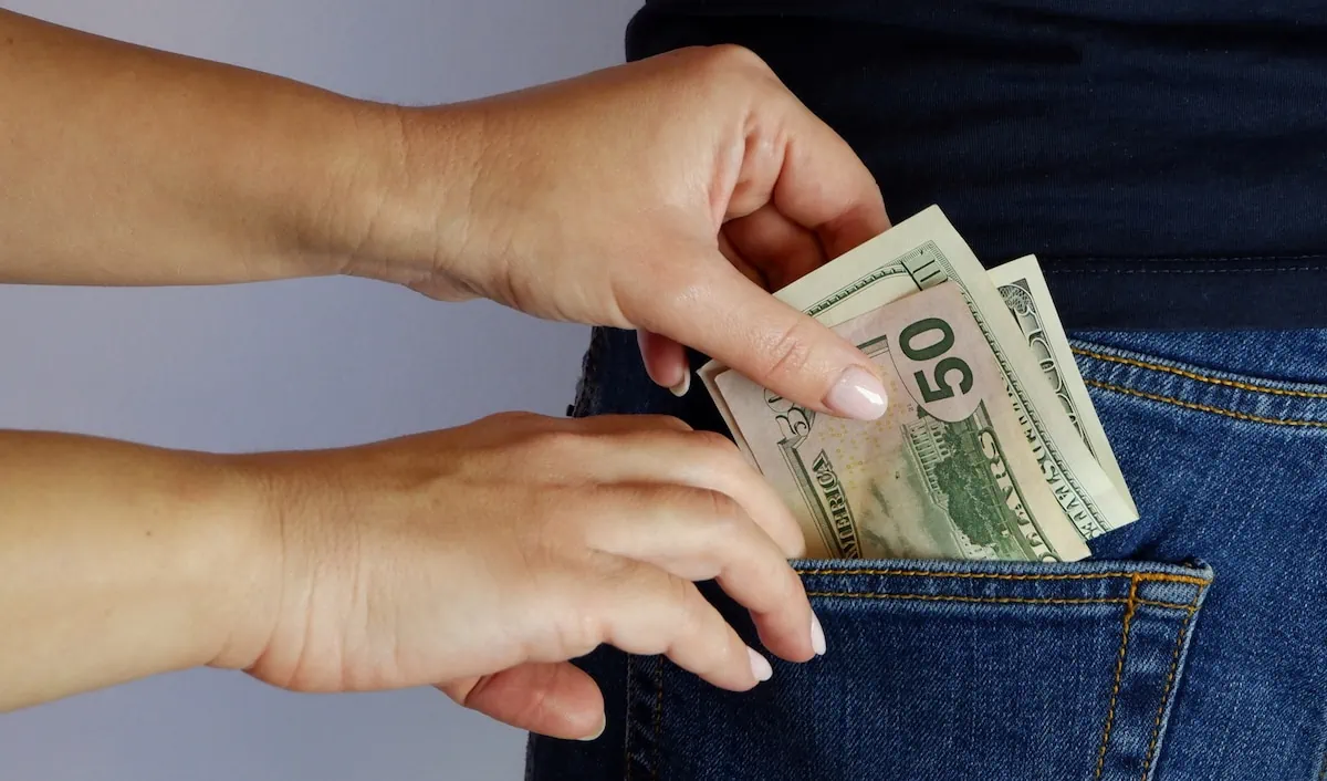 The Cost of Tradition: 7 Conventional Money Rules That Are Draining Your Wallet 2 woman pulls money out of man's back pocket