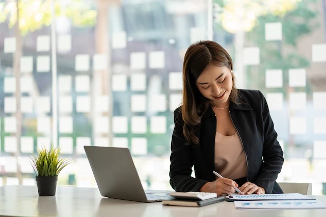 woman working at desk with charts calculator and pen