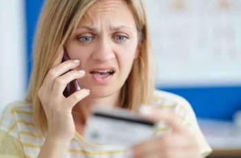 Surprised upset woman talking on mobile phone and holding bank card
