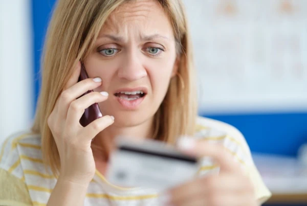 Surprised upset woman talking on mobile phone and holding bank card