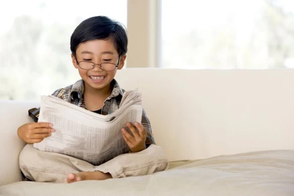 young boy on couch reading about stocks 1200