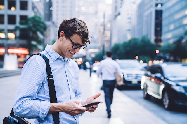 young man smiling investing smartphone app