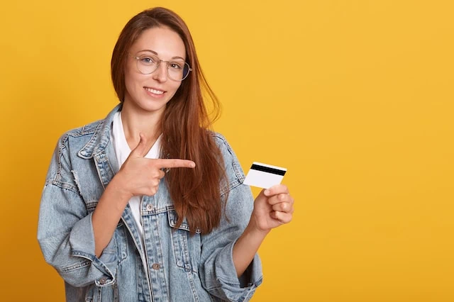 young teen with debit credit card yellow background