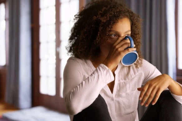 Black woman sitting alone at home with a cup of coffee