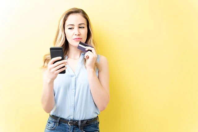 young woman credit card smartphone yellow background