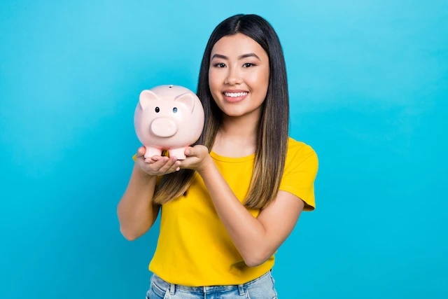 young woman holding a piggy bank and smiling