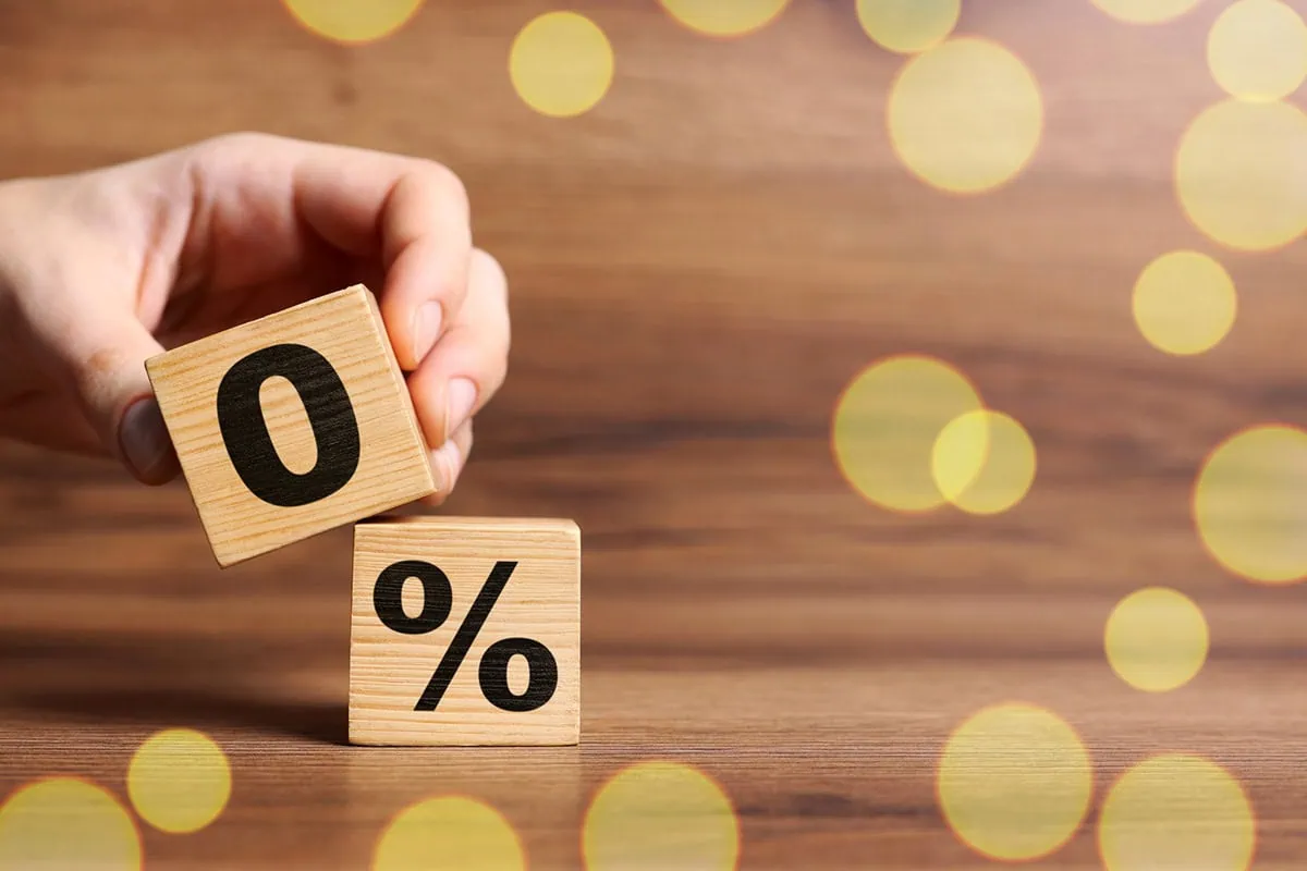 a person holds blocks that say zero and a percent sign.